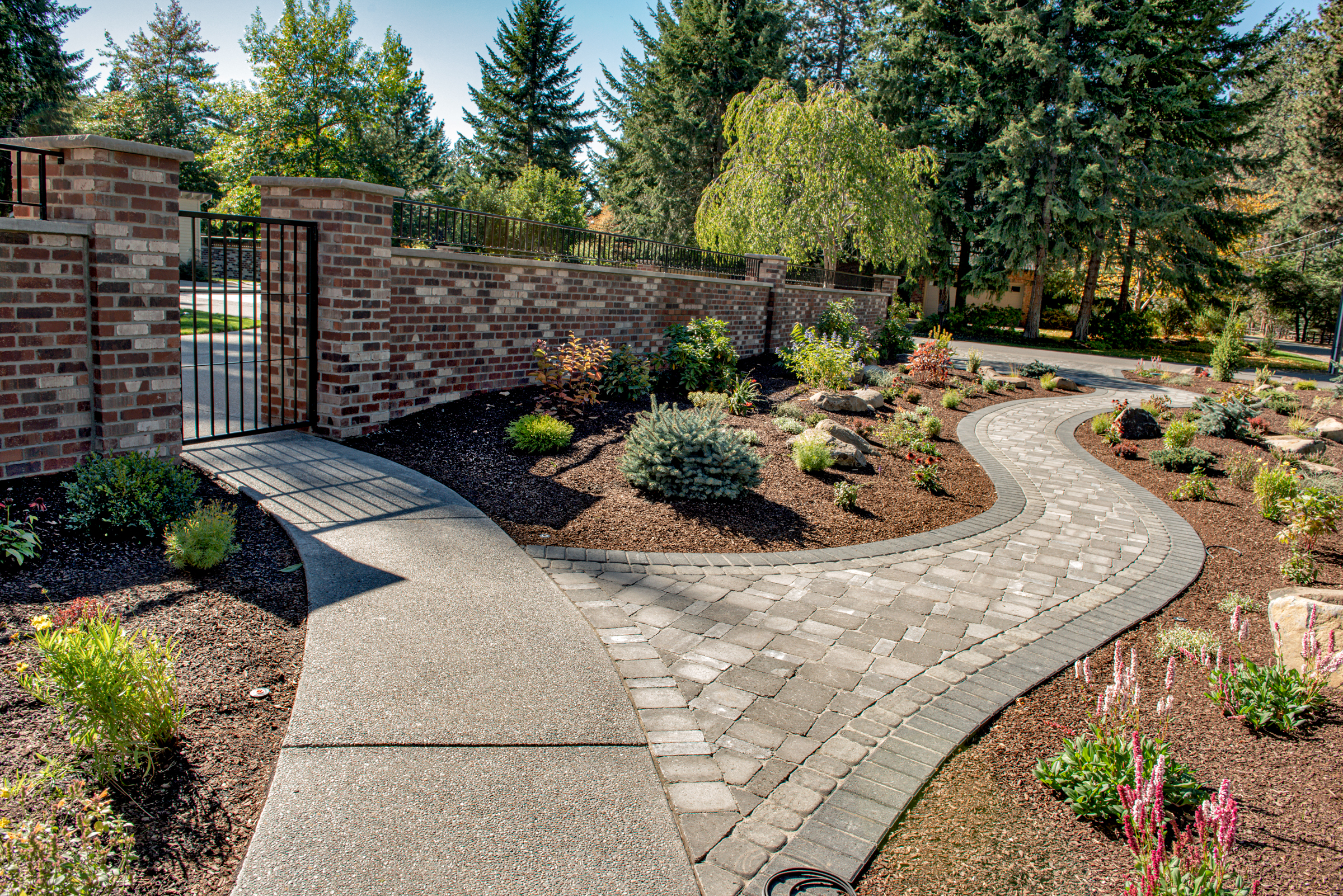 Brick wall fronted by a winding concrete paver walkway