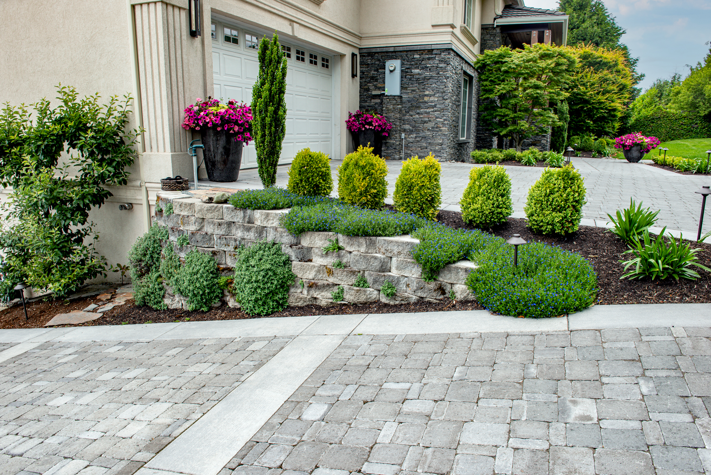 Concrete paver driveway bordered by a retaining wall