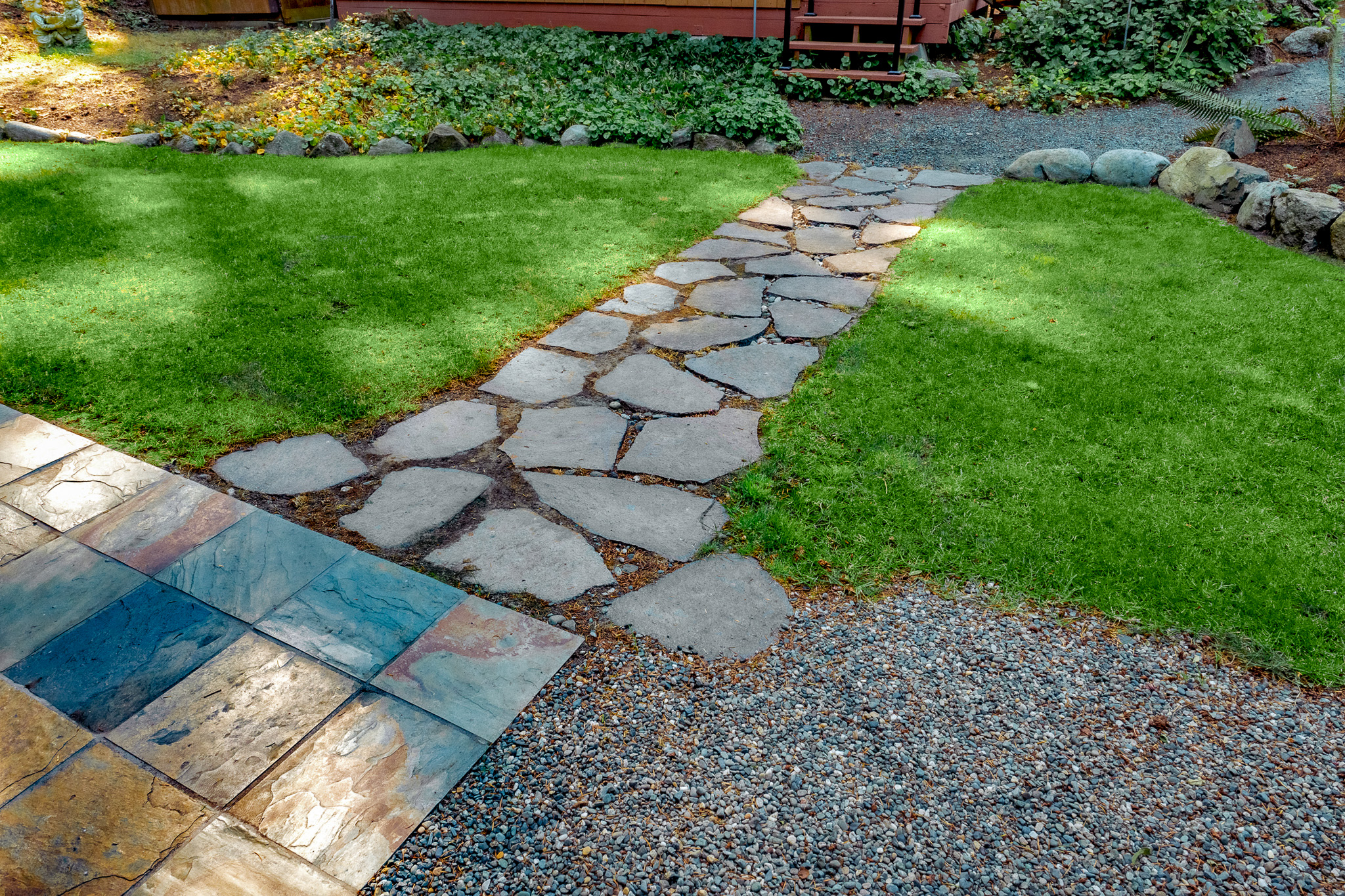 Flagstone path connects a gravel walkway to natural stone patio