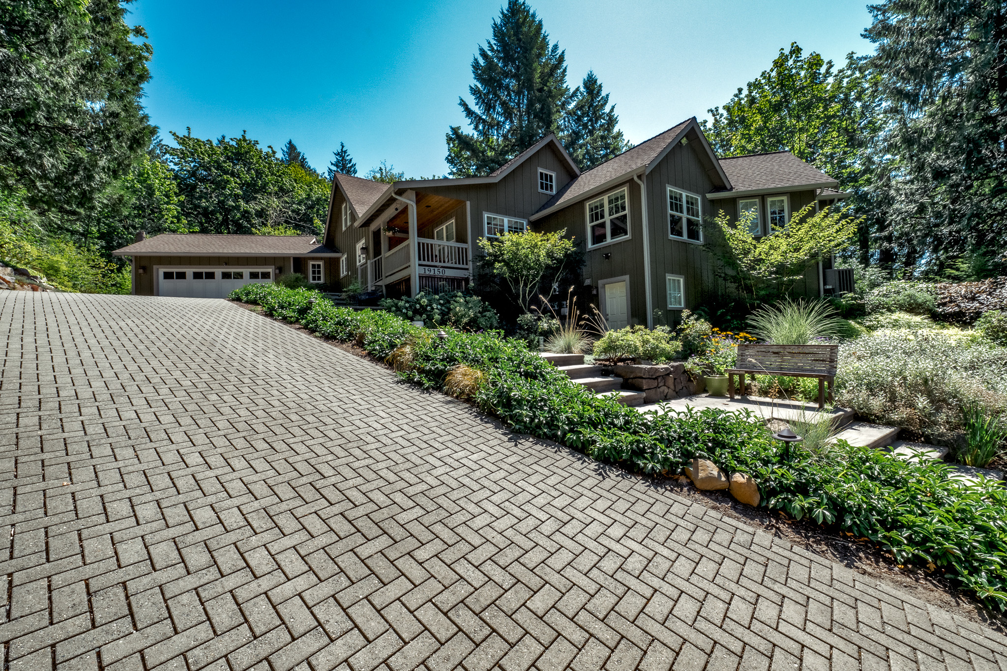 Sloped permeable paver driveway leads up to home