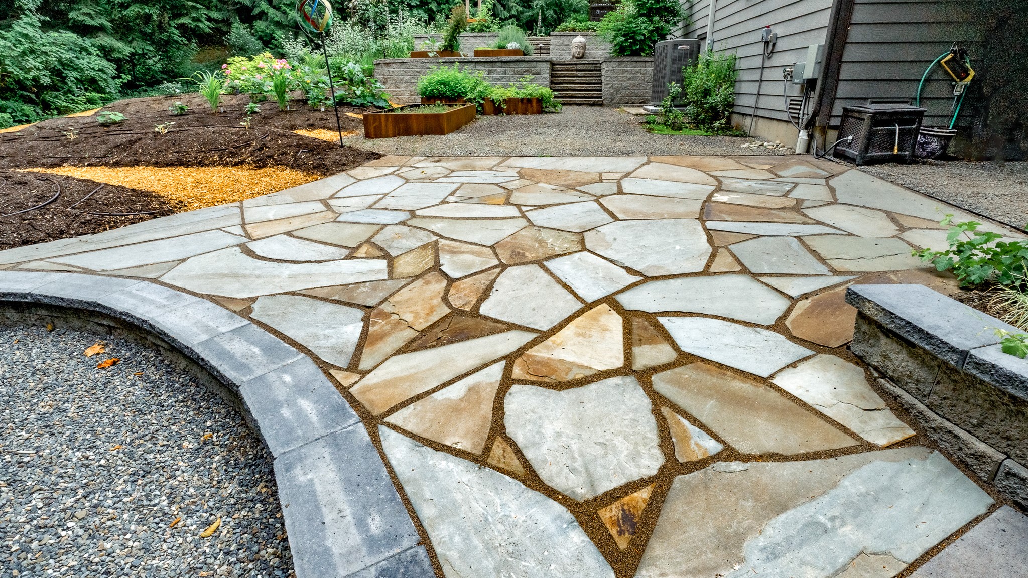 Golden flagstone patio extends off garden