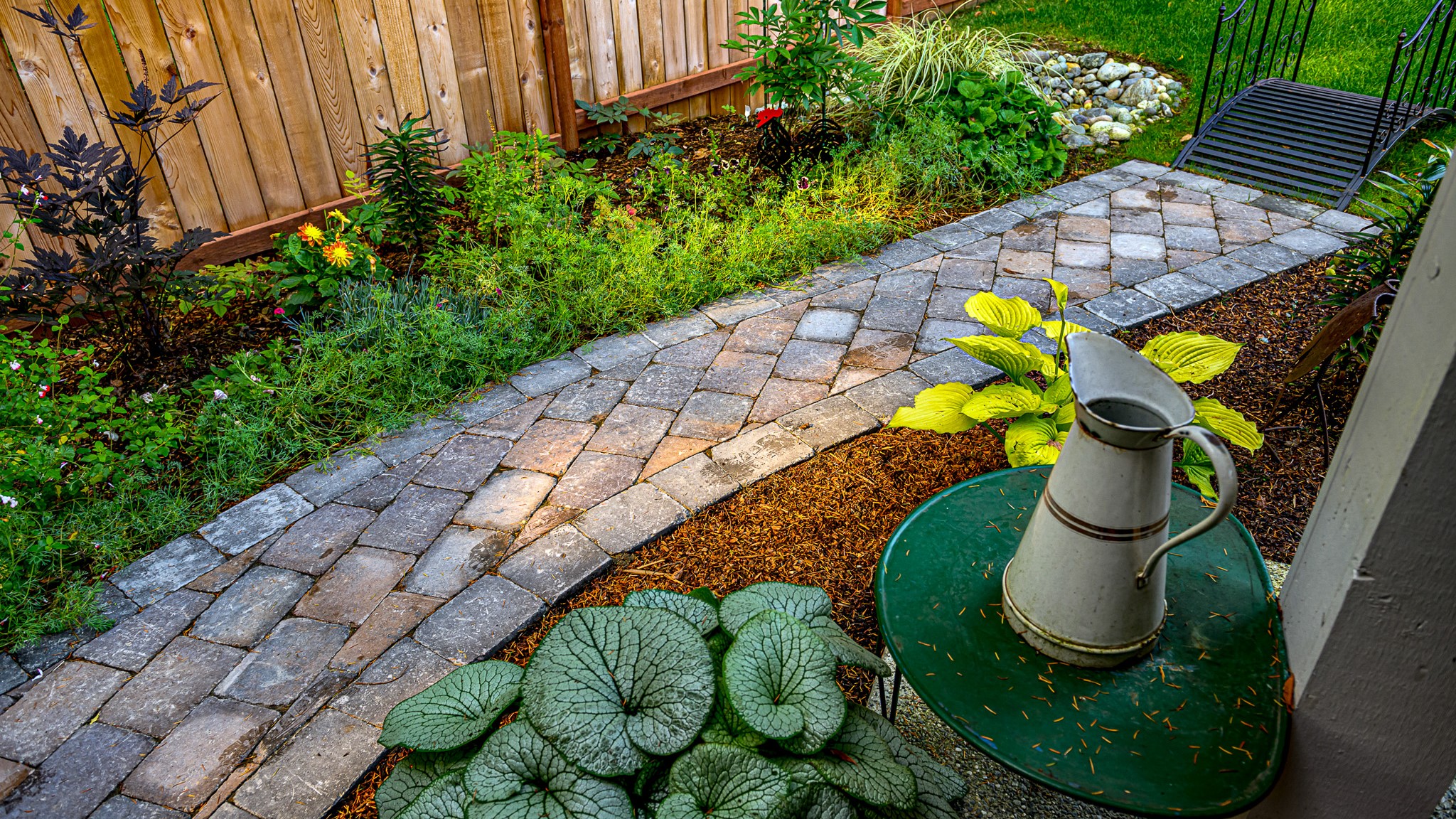 Narrow concrete paver walkway winds through a lush garden